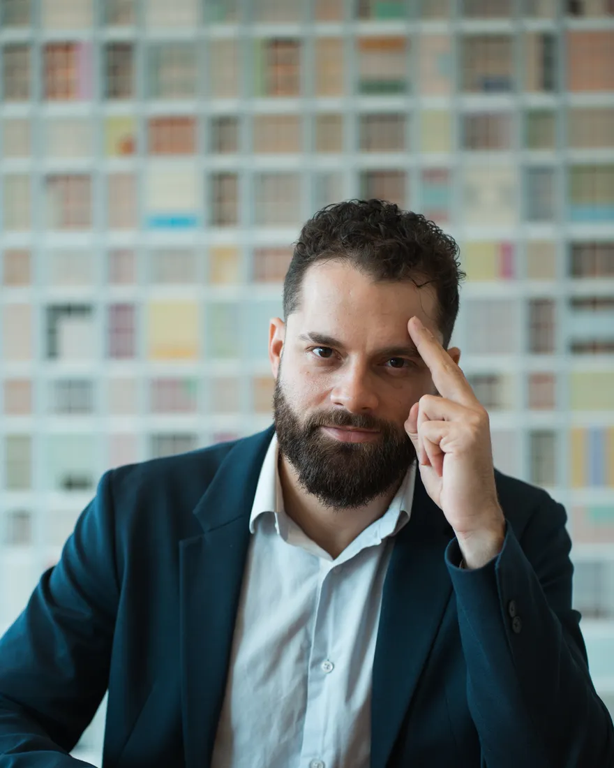 Philip Brás com o dedo na têmpora e meio sorriso, gesto de ideia